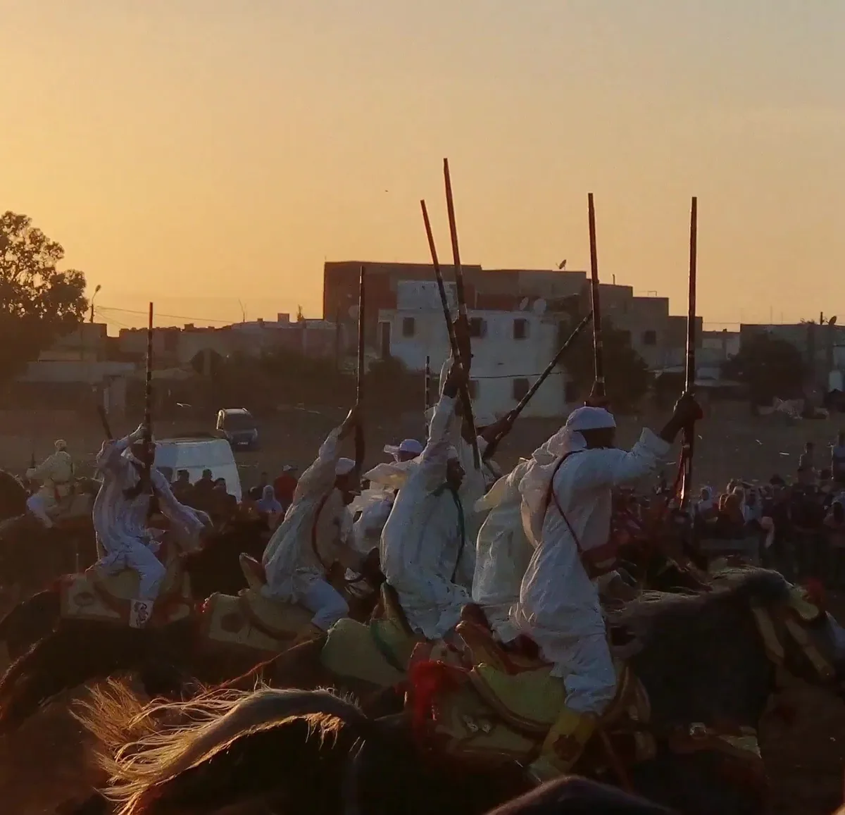 Moroccan horsemen firing muskets in a synchronised Fantasia charge at sunset
