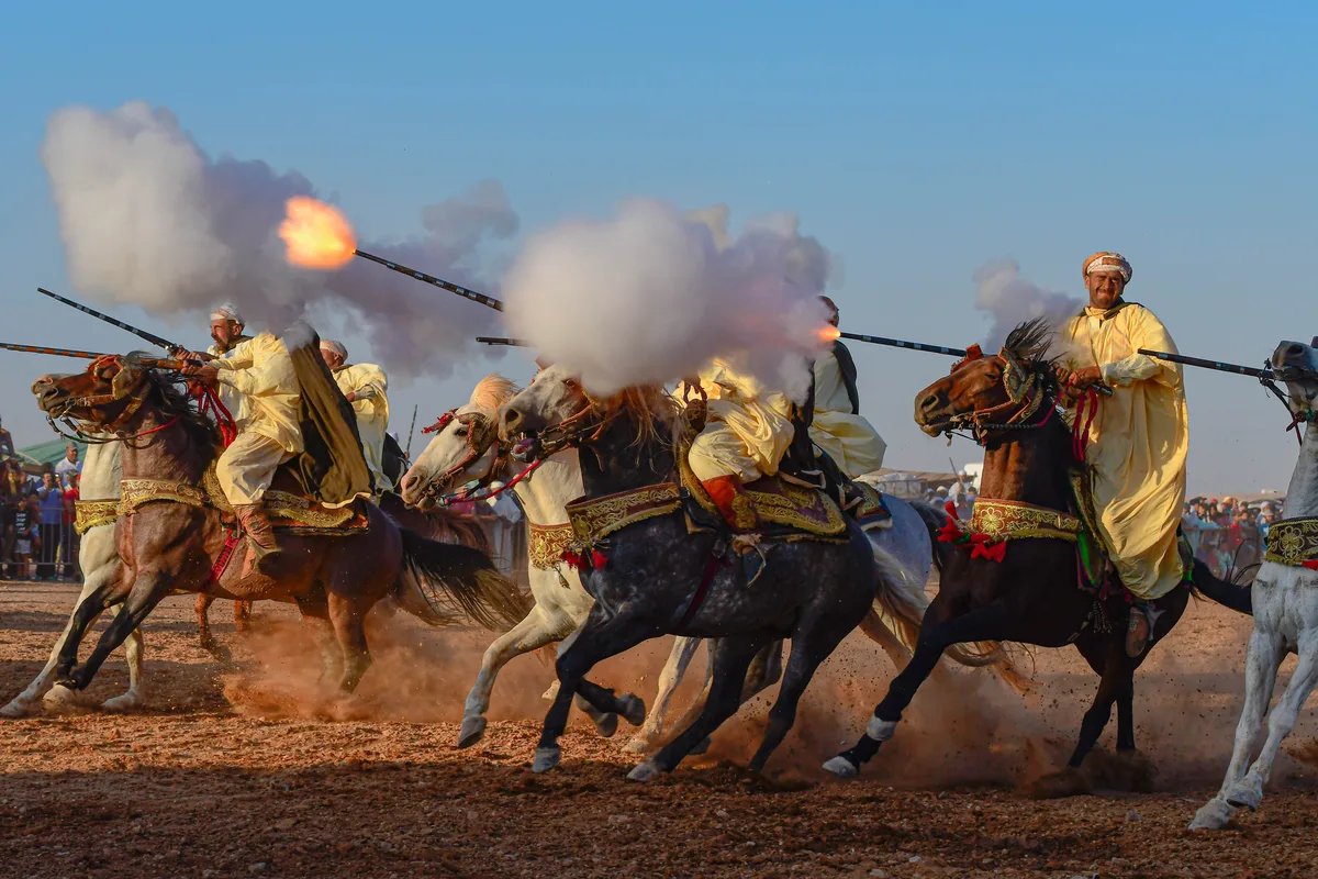 Fantasia riders raising their muskets during a tbourida display